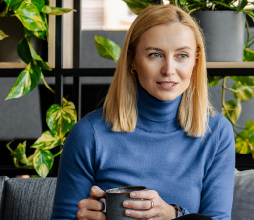7N female staff member sitting with a cup of coffee